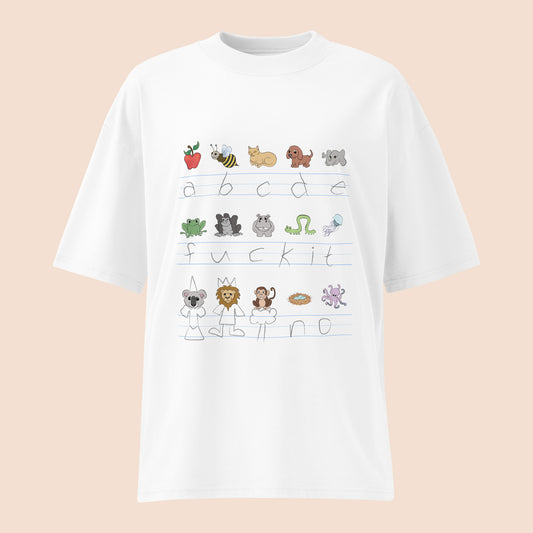 White t-shirt with handwritten alphabet text (featuring a surprise) and colourful animal illustrations on a peachy beige background