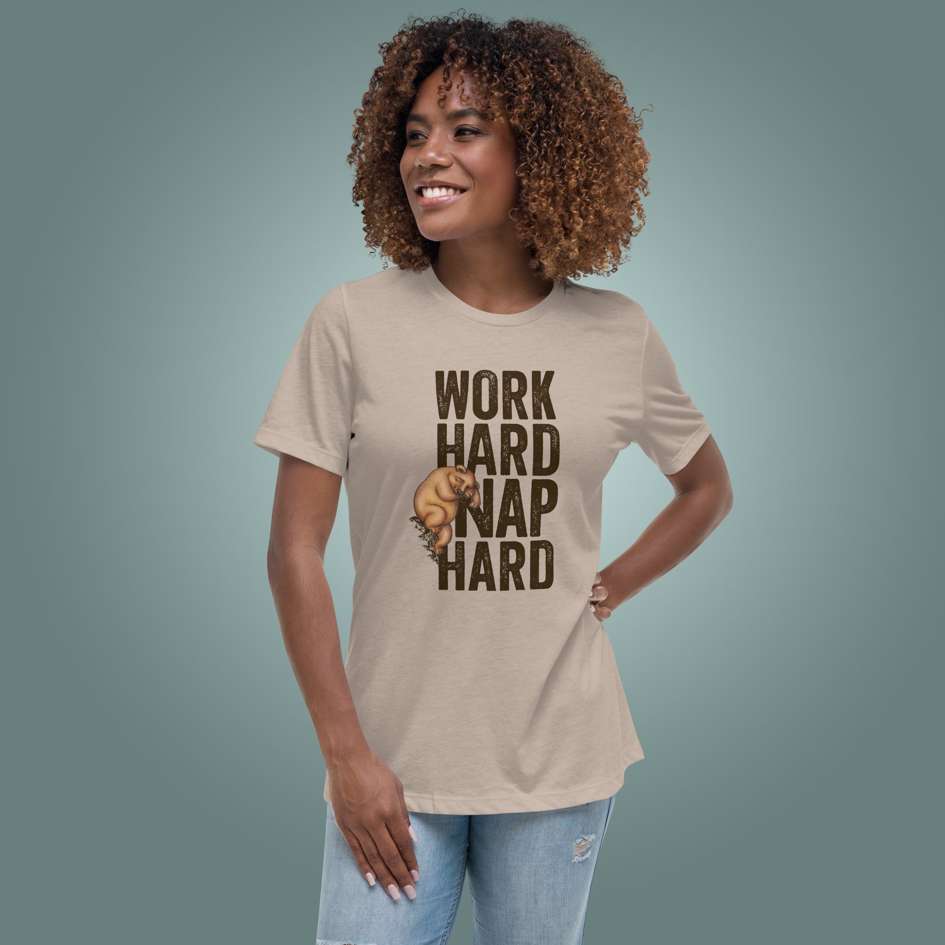 Woman wearing a beige T-shirt with 'Work Hard Nap Hard' text and a sleepy bear graphic on a teal background
