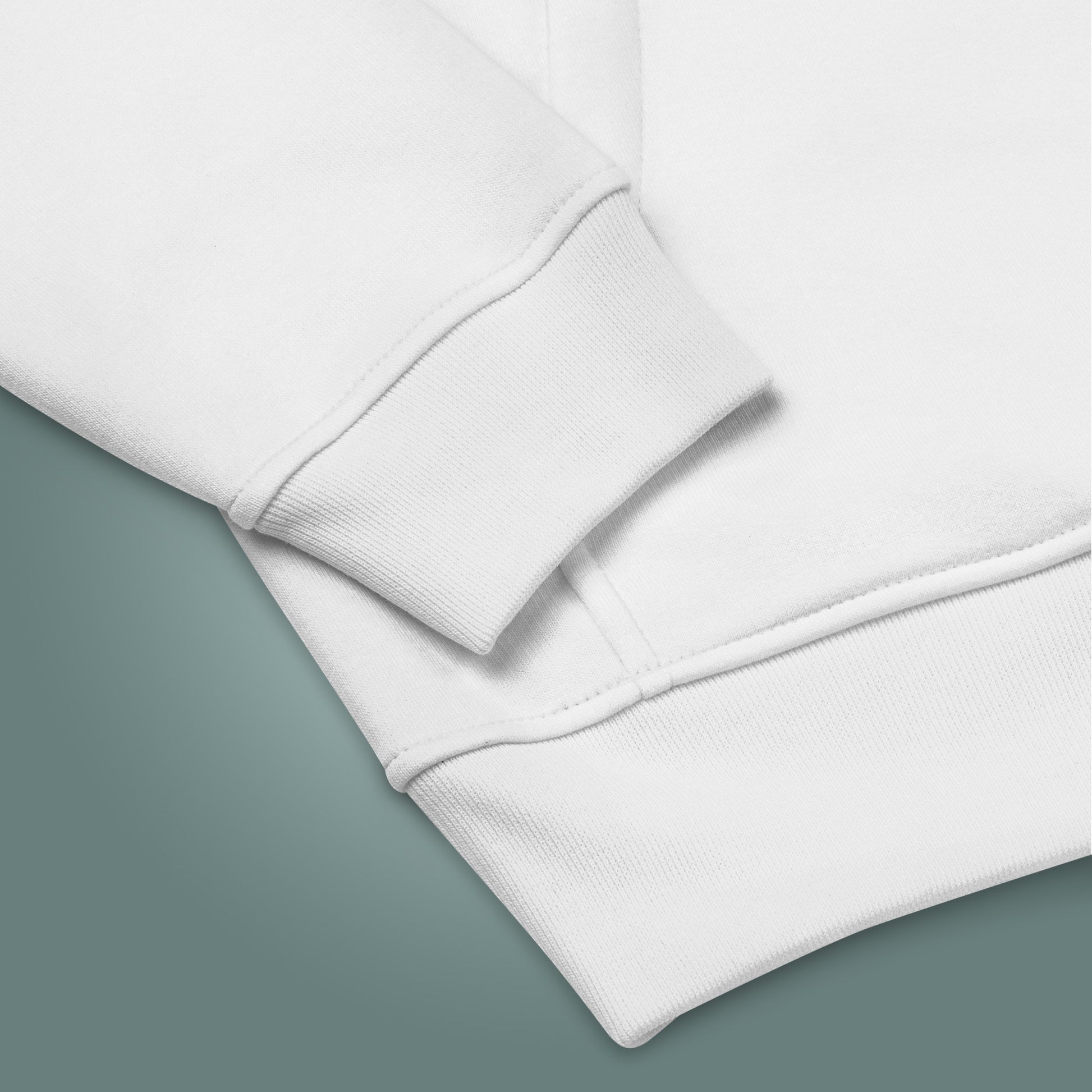 Close up of a white sweatshirt sleeve and hem on a teal background